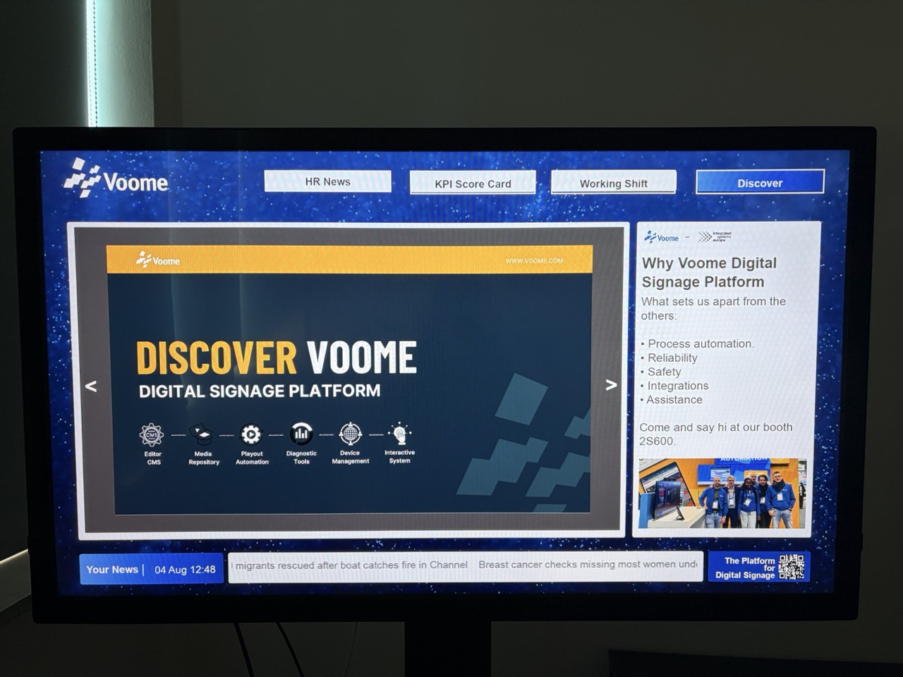 Touch screen bulletin board with buttons for HR News, KPI Score Card and Working Shift, a document in the central area, a side panel, and a news ticker
