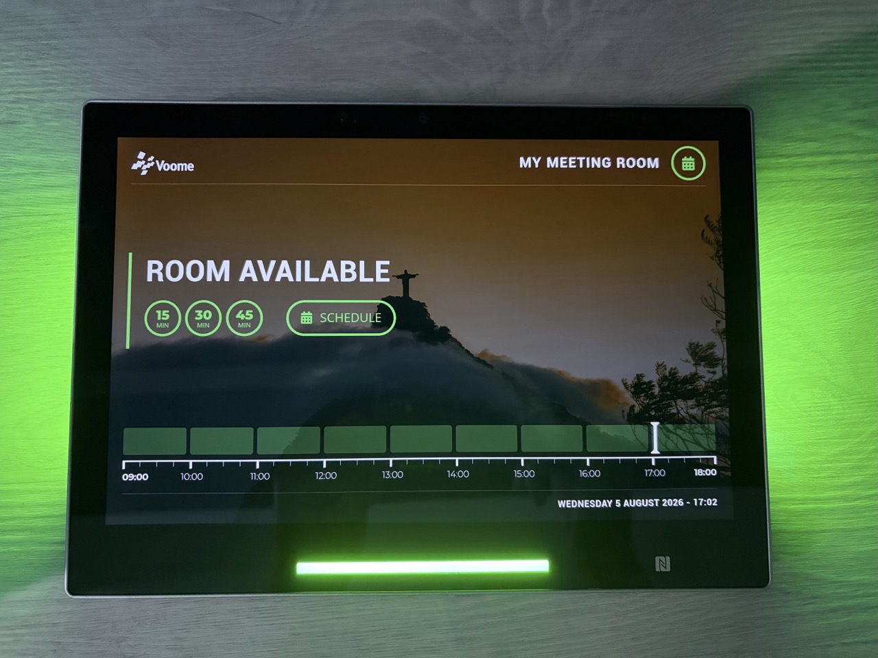 Un pannello esterno montato a parete, che mostra la schermata Room Available con il logo e lo sfondo caricati