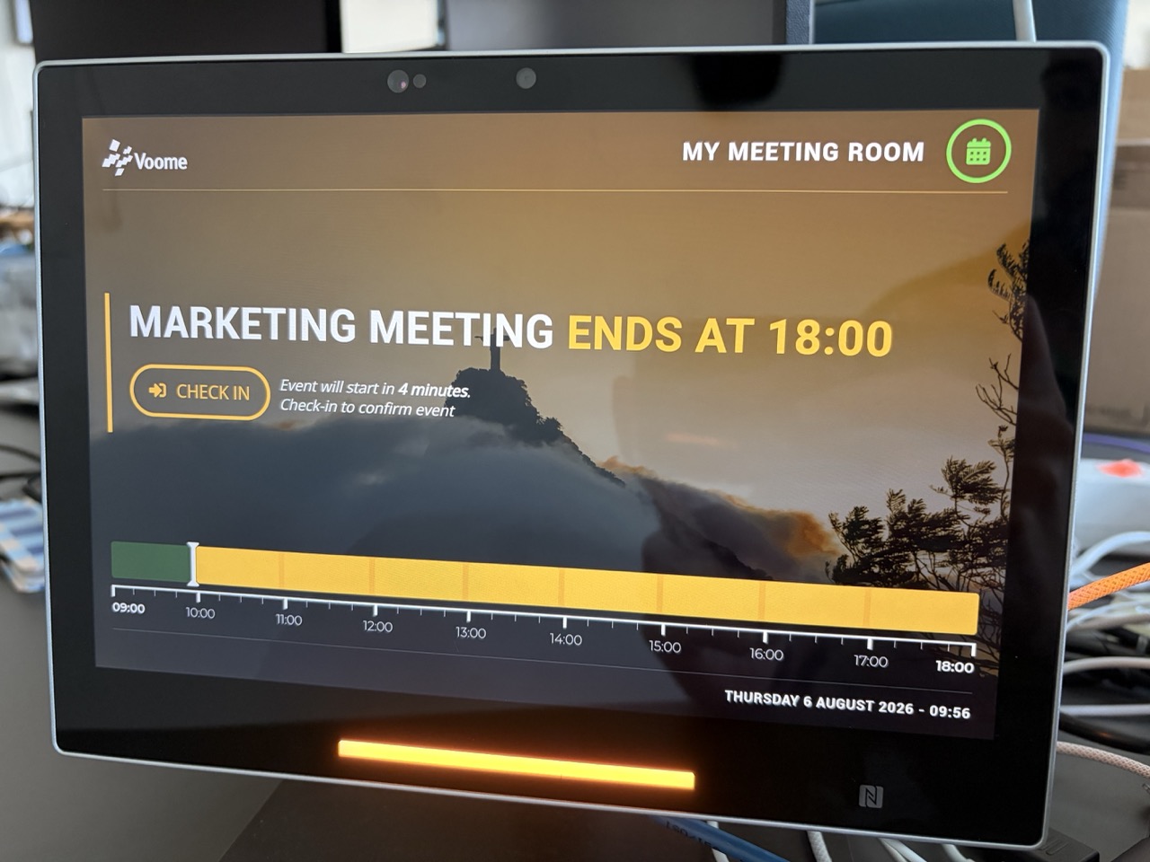 Un pannello esterno illuminato di ambra, che mostra il nome dell'evento, la sua ora di fine e un pulsante Check-in